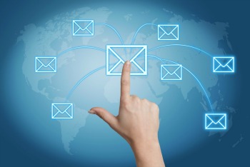 Communication concept: Hand pressing a letter icon on a world map interface