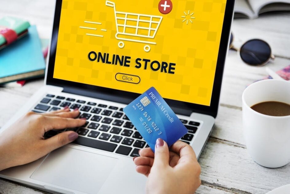 Cropped shot of a woman holding a credit card with a computer screen in front of her displaying an online store